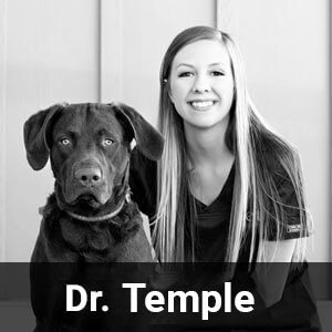 Black and white image of a woman seated next to a large dog with floppy ears, both looking at the camera. The woman has long, straight hair and is smiling. The bottom of the image contains the text "Dr. Temple.