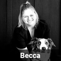 Black and white photo of a person smiling and kneeling behind a dog. The word "Becca" is displayed at the bottom of the image.