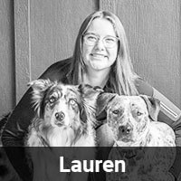 A person with long hair and glasses smiles while sitting with two dogs. The image is in black and white, and the name "Lauren" is displayed at the bottom.