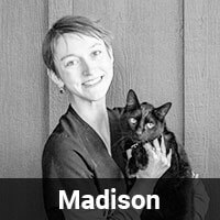 A smiling person holding a black cat poses in front of a wooden wall. The image is in black and white, and the name "Madison" is written at the bottom.