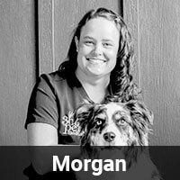 A person with long hair smiling and sitting next to a dog. The background is a paneled wall. The text "Morgan" appears at the bottom of the image.